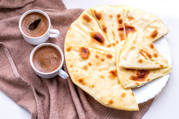 Homemade freshly baked flat bread stuffed with cottage cheese on a table with two mugs of coffee