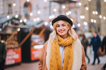 Portrait of a cute smiling young woman visiting outdoors Christmas market.