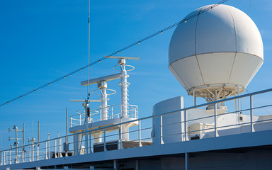 White color satellite antenna of cargo a ship and sun loungers on deck of cruise ship