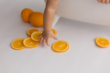 the child is holding a slice of orange orange. child's hand. fruits