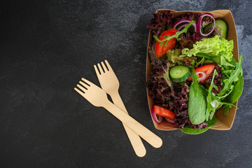 Healthy salad, leaves mix salad in paper disposable tableware (mix micro greens, cucumber, tomato,...