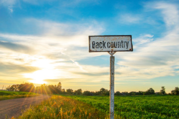 road sign in a beautiful countryside on a summer evening, a great secluded place on a sunset background. Backcountry