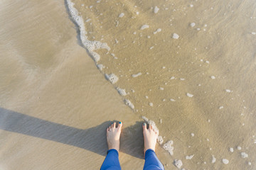 Fototapeta na wymiar relax women feet on the beach with water