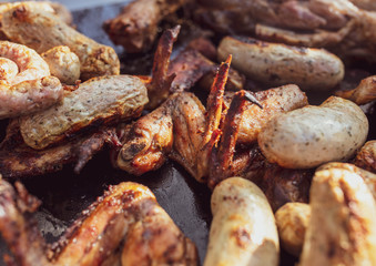 Grilled sausages and chicken legs on charcoal grill