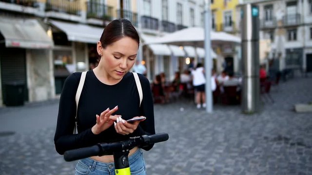 A woman using a mobile phone for unlocking an electric scooter by app