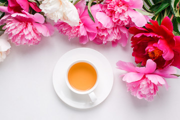 Fototapeta na wymiar Peonies and cup of tea on white background. Spring flowers. Spring breakfast background. Greeting card for Valentine's Woman's Mother's Day, wedding.