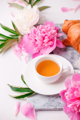 Peonies and cup of tea on white background. Spring flowers. Spring breakfast background. Greeting card for Valentine's Woman's Mother's Day, wedding.