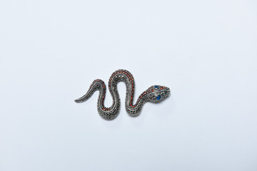 Handcrafted antique brooch in the shape of a snake with colorful stones