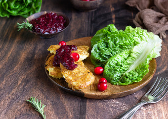 Traditional Viennese chicken schnitzel served with cranberry sauce and green salad. Wooden background. Chicken steak in breading, sauce and fresh salad. 