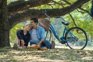 young couple talking together and sitting picnic with bike in park at summer. love and Valentines...