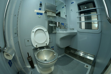 Toilet in a railways sleeping carriage of a passenger train – toilet-bowl, washbasin, mirrors and toilet paper box