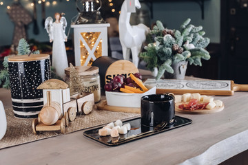 Festive Christmas decoration table with big cup of hot beverage with sugar and snack close-up. Cosiness december season decorating ready to coffee break at cozy room celebrating New Year holiday