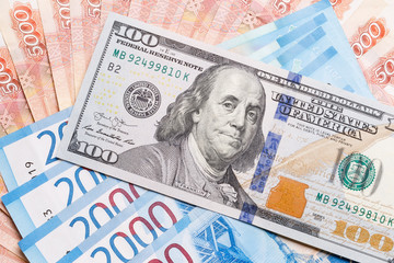 Obraz na płótnie Canvas A bill of one hundred US dollars against the background of five thousandths and two thousandths will buy Russian rubles. The concept of exchange transactions, strong currency, excellence.