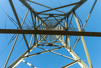 Strommast von unten in der Mitte im Sonnenlicht mit blauem Himmel