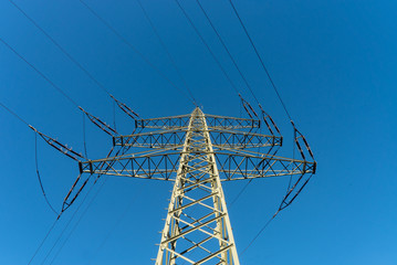 Strommast von unten im Sonnenlicht mit blauem Himmel