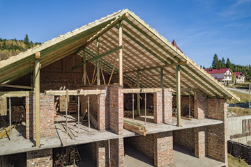 Wooden frame of new roof on a brick big house under construction.