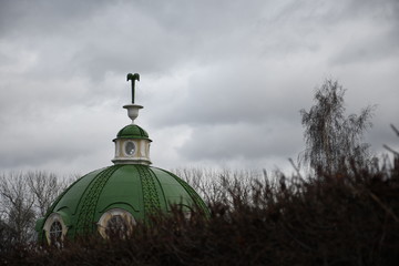 dome of the old palace in Moscow. grey sky. tree branches. green dome with round windows.  Kuskovo palace in Moscow.