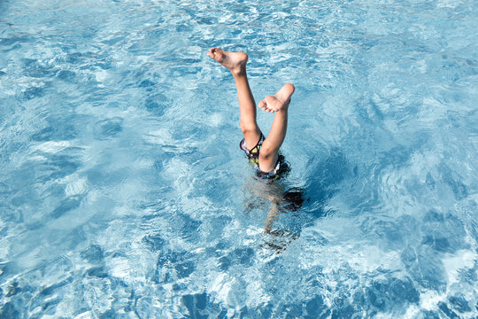 A Boy Does A Handstand In The Swimming Pool
