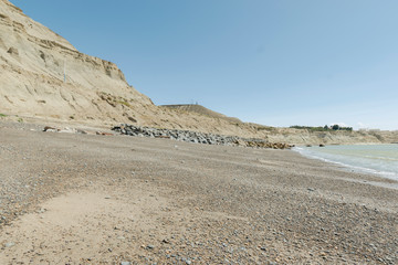 Small rocky beach with view of cliffs and sea on a sunny day