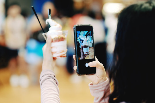 A girl take a picture of ice cream by smartphone