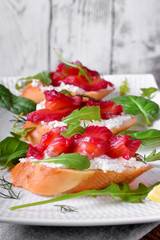 Trout Gravlax on the slices of white bread with ricotta topped with greenery against the white background. Nordic cuisine meal