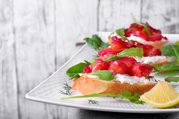 Trout Gravlax on the slices of white bread with ricotta topped with greenery against the white background. Nordic cuisine meal