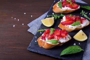 Trout Gravlax on the slices of white bread with ricotta topped with greenery on the stone platter. Nordic cuisine meal
