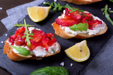 Trout Gravlax on the slices of white bread with ricotta topped with greenery on the stone platter. Nordic cuisine meal