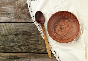 empty brown ceramic plates and wooden spoon on a wooden table
