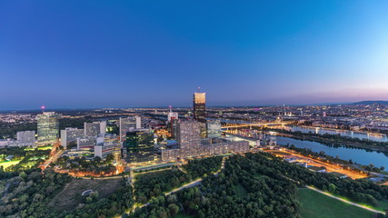 Aerial panoramic view over Vienna city with skyscrapers, historic buildings and a riverside promenade day to night timelapse in Austria.