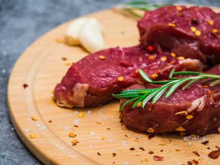 Fresh uncooked meat with rosemary, spices, herbs and garlic on cutting board. Raw Beef Steak Seasoned and Ready to be Cooked