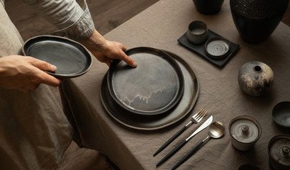 man holding dark handmade ceramic plates