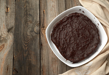 baked brownie chocolate cake in a white ceramic plate on a gray wooden background