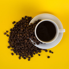 cup of coffee with coffee beans on yellow background