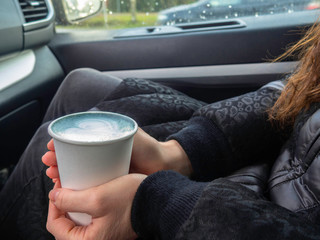 Blue matcha latte art in eco friendly paper cup. Main color 2020 year concept. A cup of coffee female hands in car. Minimal composition.