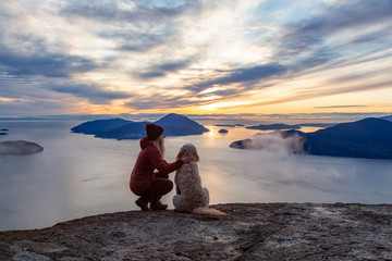 Adventurous Girl Hiking on top of a Mountain with a dog during a colorful sunset. Taken on Tunnel...