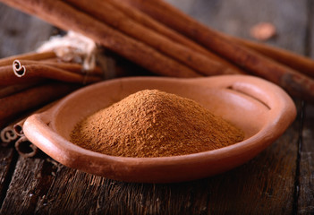 powder of cinnamon in a pottery on wooden table
