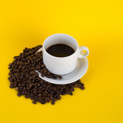 cup of coffee with coffee beans on yellow background