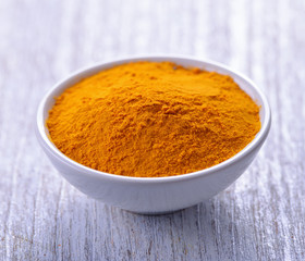 Turmeric powder in white bowls on wooden table. herbal
