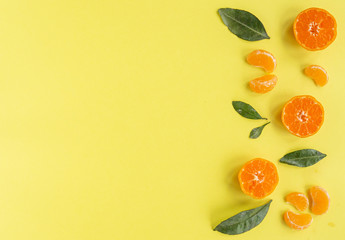 Flat lay with orange tangerines, mandarin slices on yellow background.  Top view, copy space.  