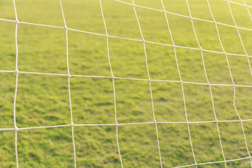 Close up of white soccer / football net goal white green nature grass field under sunlight using as sport wallpaper or background.