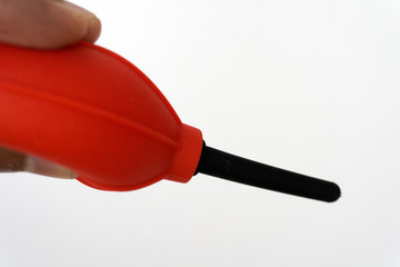 Red and black camera air blower for clearing dust particles from lens.