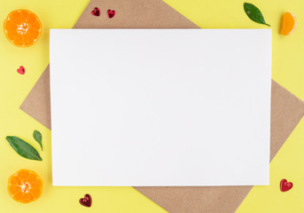 Minimalistic card mockup with envelope, postcard, pen, tangerines, slice of mandarin, red hearts on yellow background. Flat lay, top view, copy space. Valentines day, birthday concept.