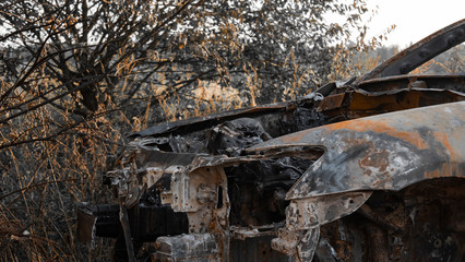 Burnt out car. Burned out engine. The car without a hood, ash and garbage after a fire. Arson of a car near a forest near the city. The concept of a traffic accident and vandalism or crime.