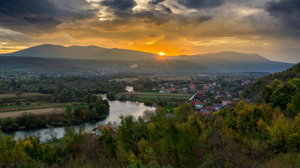 Dramatic view of sun rising over hillsside and river after a storm 