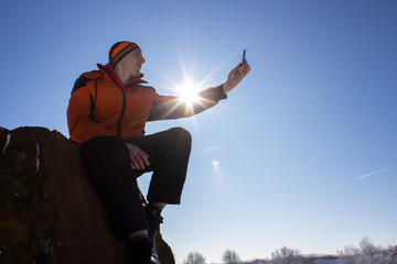 selfie in winter on rock,man at sunset photographing himself on a rock in winter, selfie at sunset