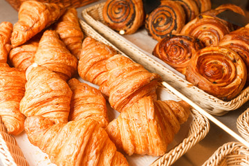 Delicious freshly baked pastries in a pastry shop. Many buns and croissants on a shelf of a baking shop