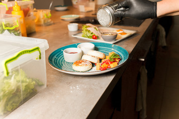 Restaurant’s cook has prepared delicious cheese pancakes and sprinkles them with powder
