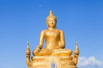 The golden Buddha made of 22 tons of brass and 12 meters high, inside the temple of popular and largest Bid Buddha in Chalong, Phuket, Thailand in the blue sky. Peace and meditation concept.