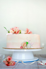 Obraz na płótnie Canvas Delicate pink wedding cake with natural fresh beautiful flowers roses and lily. How To Put Fresh Flowers On A Buttercream Cake. Adding fresh flowers on a cake
